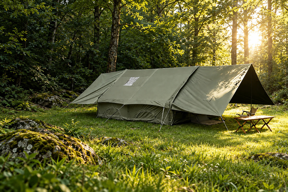 Army green Cabin tent with both end extensions raised in a forest clearing.