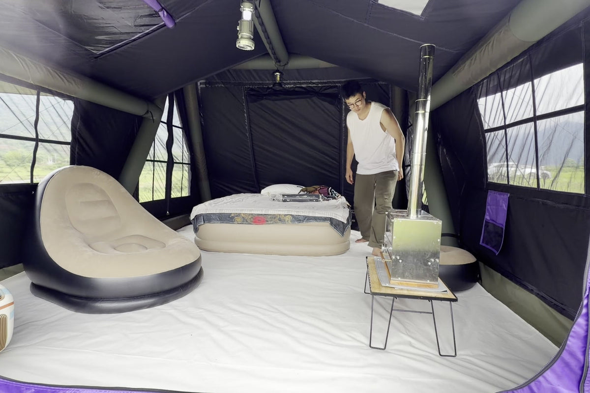 Furnished purple A-Frame interior with a bed, lounge chair and a person for scale.