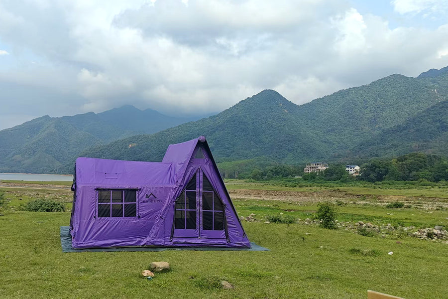 Purple A-frame inflatable tent pitched on a grassy mountain campsite