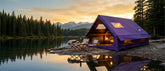 Purple inflatable glamping tent set up by a forest lake at sunset.