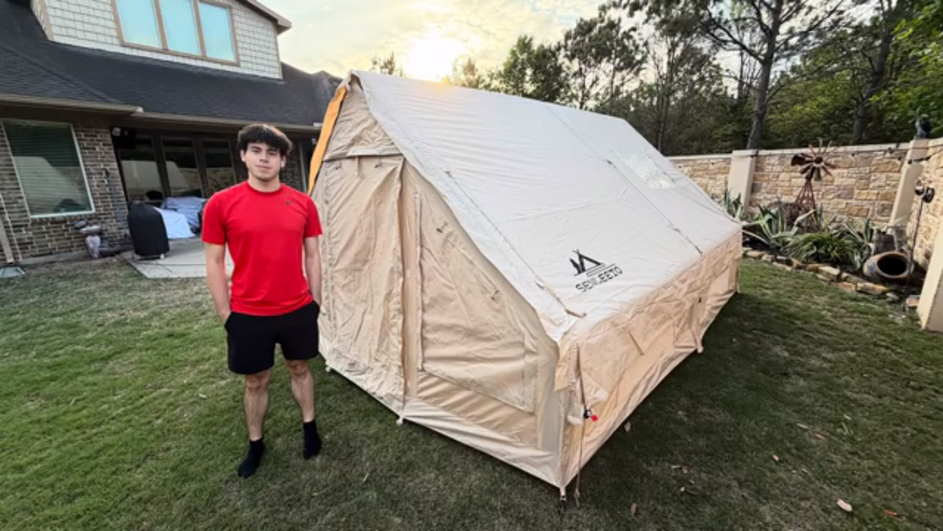 Teen standing next to Senleeto inflatable glamping tent set up in backyard at sunset