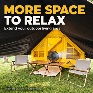 Outdoor seating area beneath the yellow tent canopy, with camping chairs, a table and a fan.
