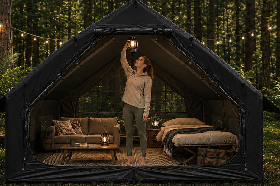 A woman hanging a lantern inside the large entrance of a black Cabin tent