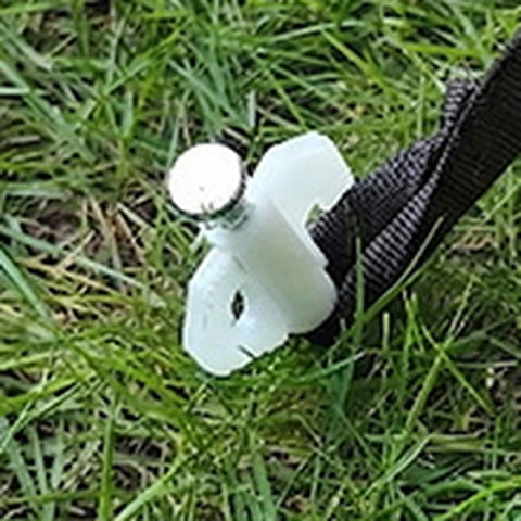 Ground peg and securing strap on grass beside the yellow Cabin tent