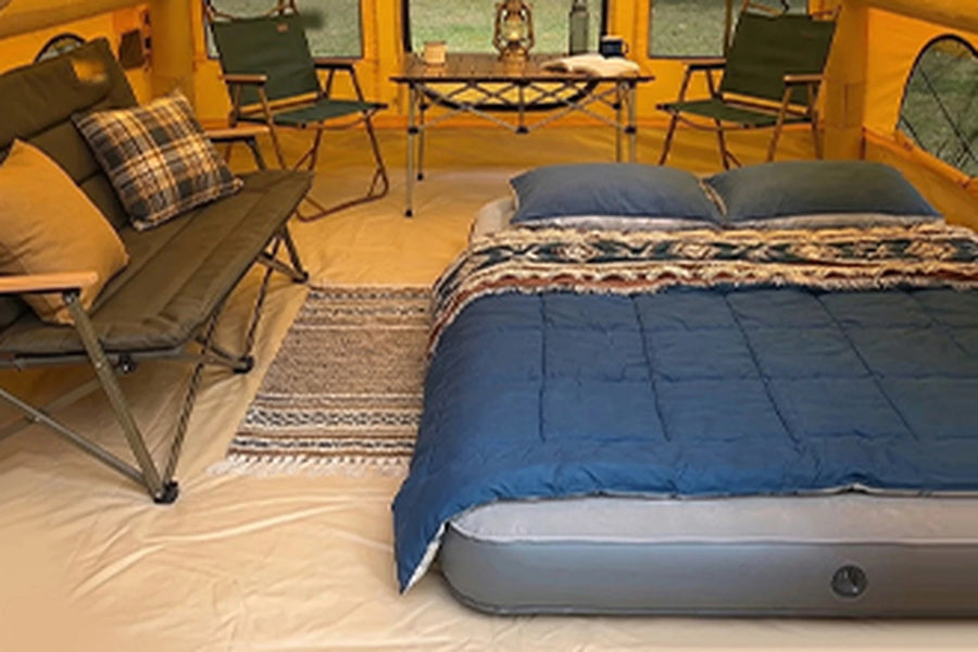 Bed, folding table and chairs inside the yellow Cabin tent