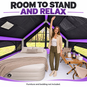 A camper standing inside the purple blackout cabin tent beneath the peaked roof.