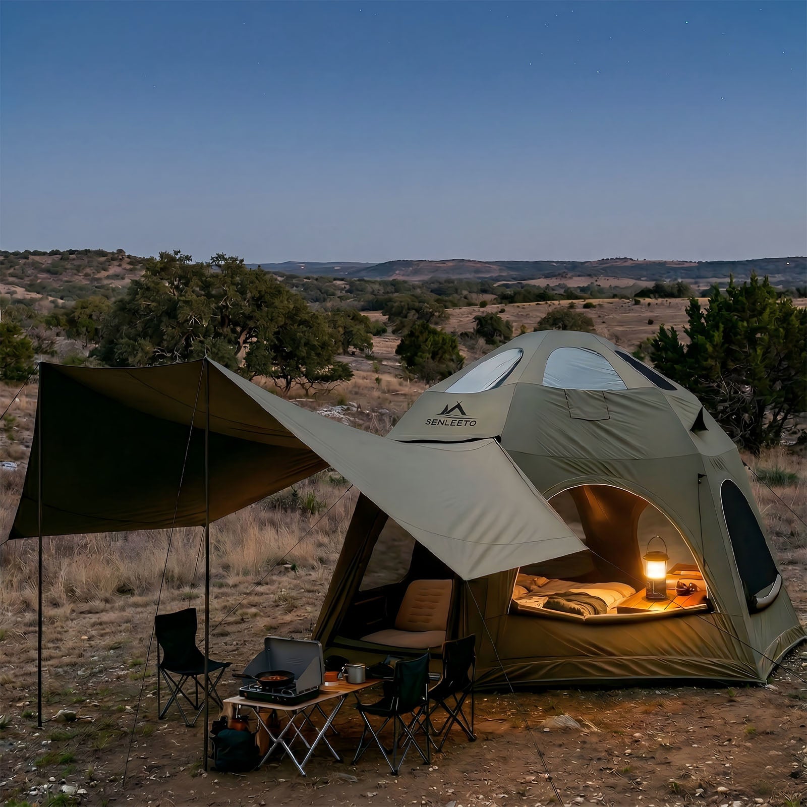 Senleeto TC cotton inflatable dome tent in olive green, set up in the wilderness at dusk with warm interior lights.